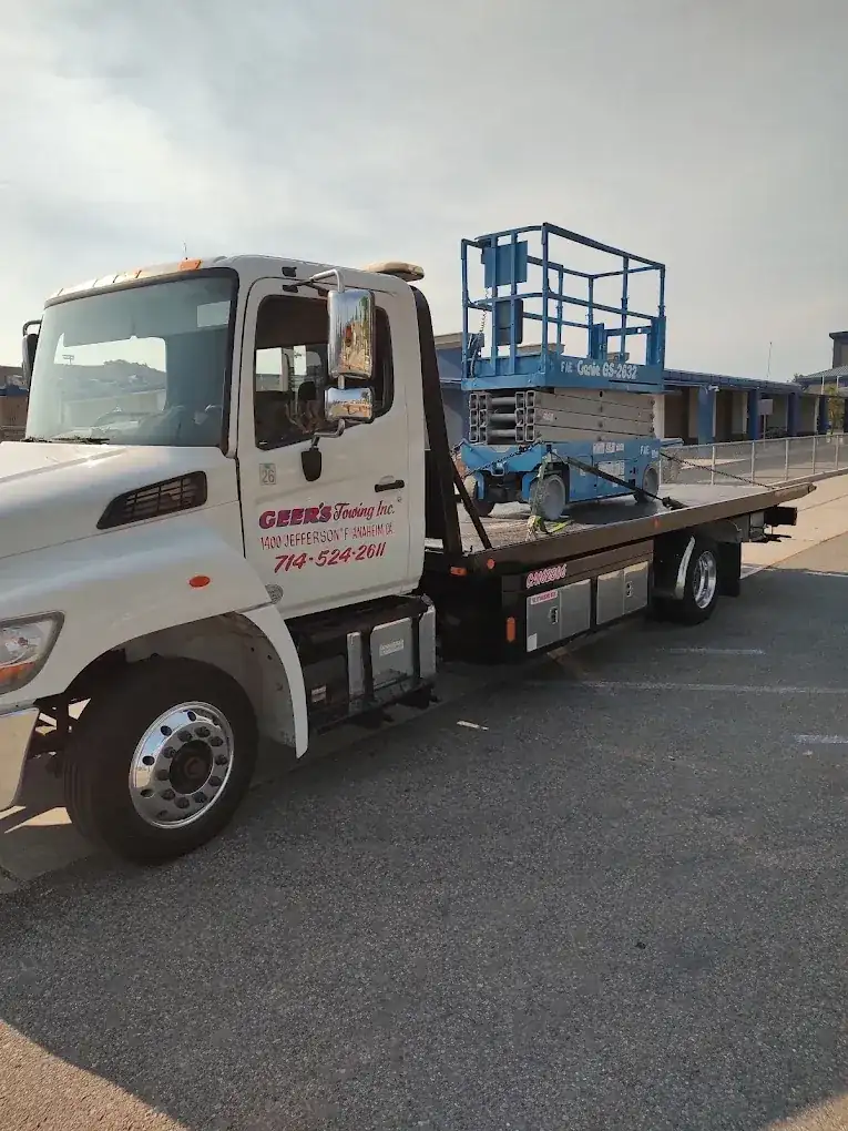 Geer's Towing flatbed hauling a Genie scissor lift for equipment transport