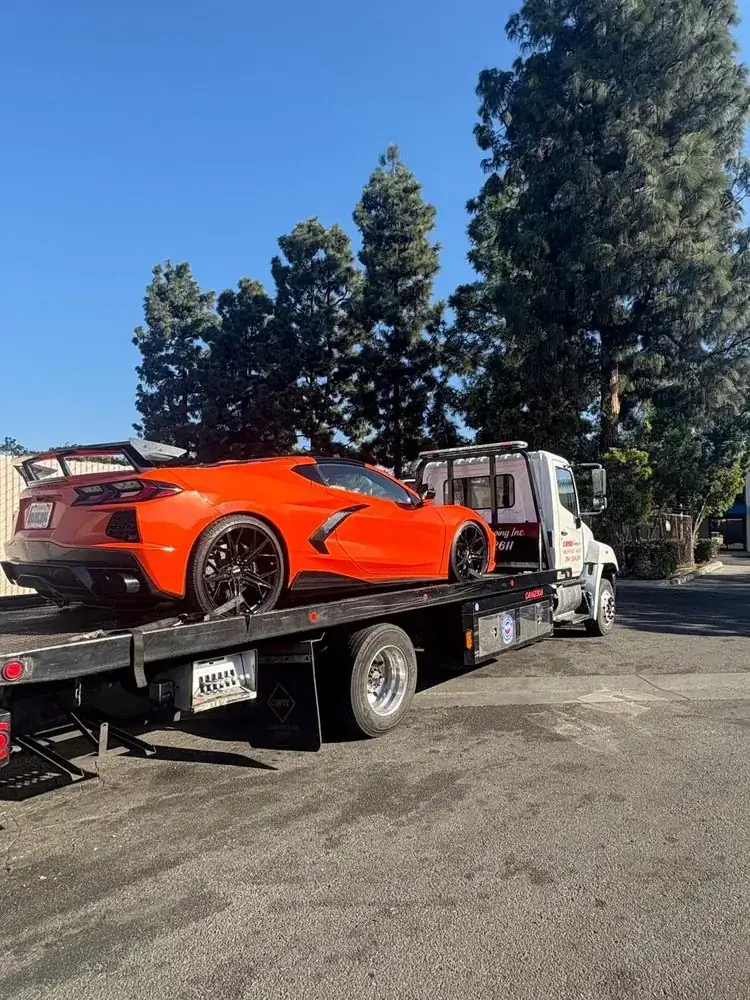 Geer's Towing flatbed transporting an orange Chevrolet Corvette
