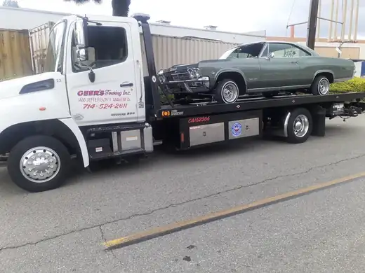 Geer's Towing flatbed tow truck safely transporting a classic Chevrolet Impala in Anaheim, California