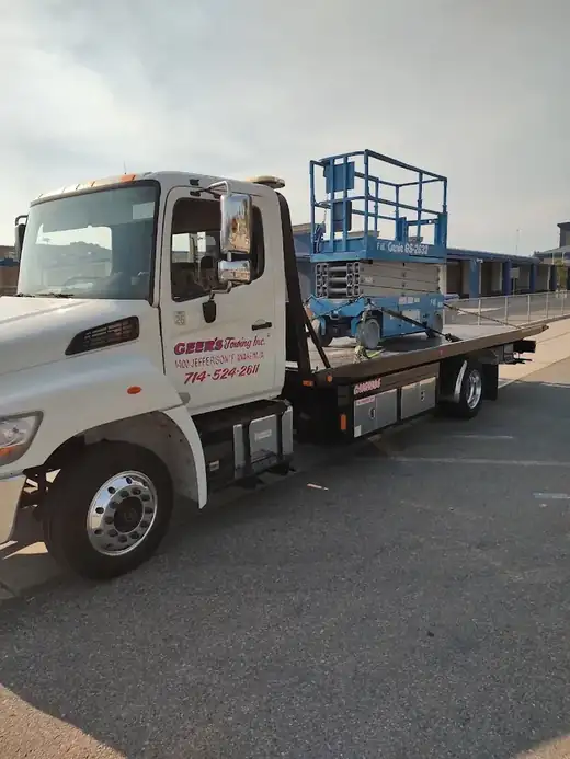 Geer's Towing flatbed hauling a Genie scissor lift for equipment transport